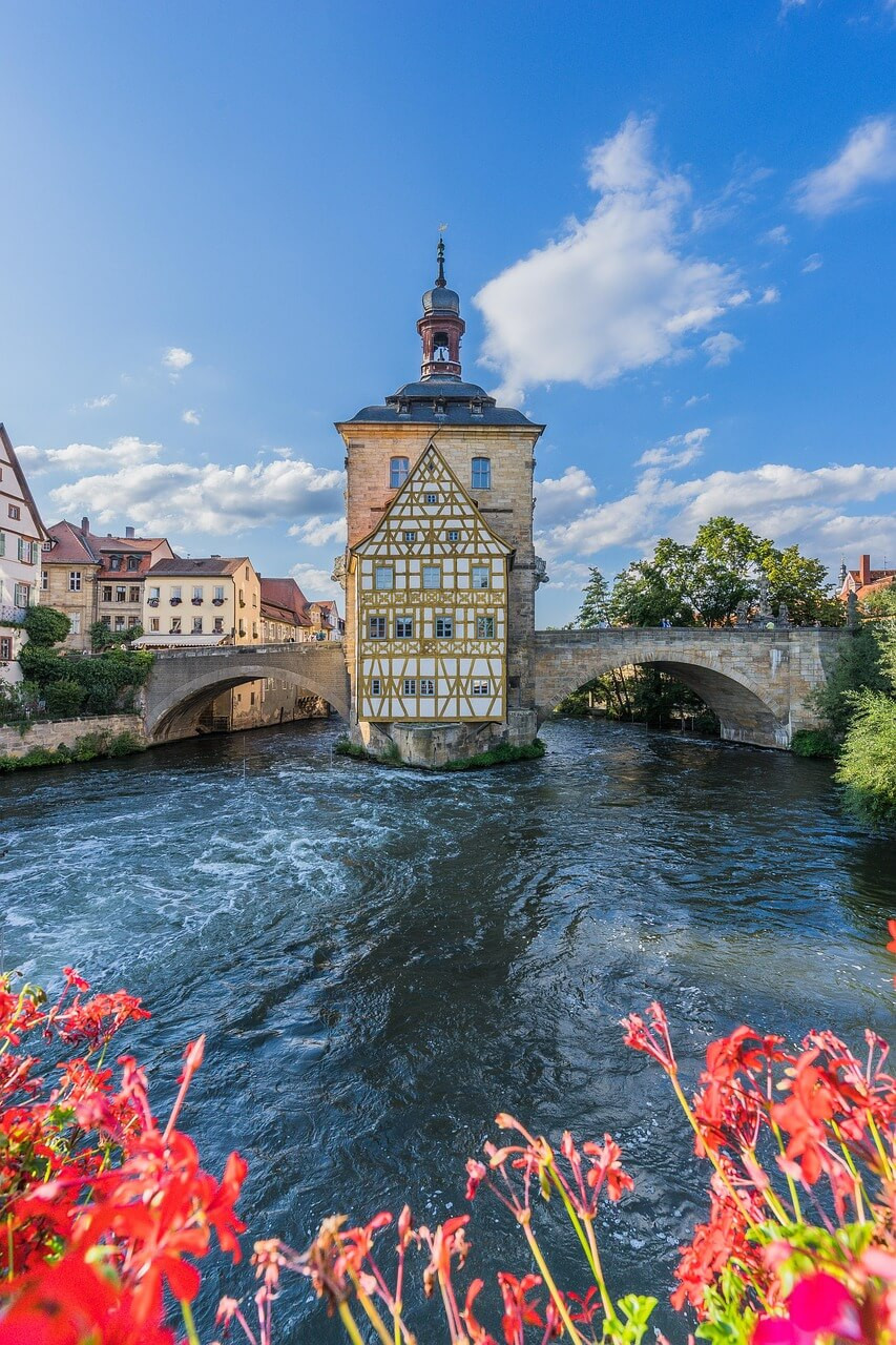 Altes Rathaus in Bamberg auf einer Brücke über der Regnitz mit Blumen im Vordergrund