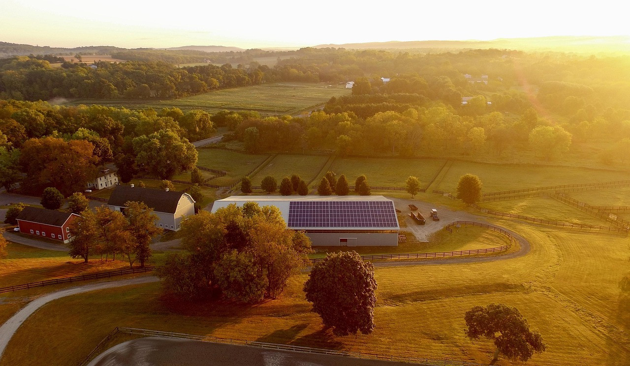 Photovoltaikanlage auf einem landwirtschaftlichen Gebäude inmitten einer ländlichen Landschaft bei Sonnenuntergang - Beispiel für netzunabhängige Speicherlösungen von Sunna