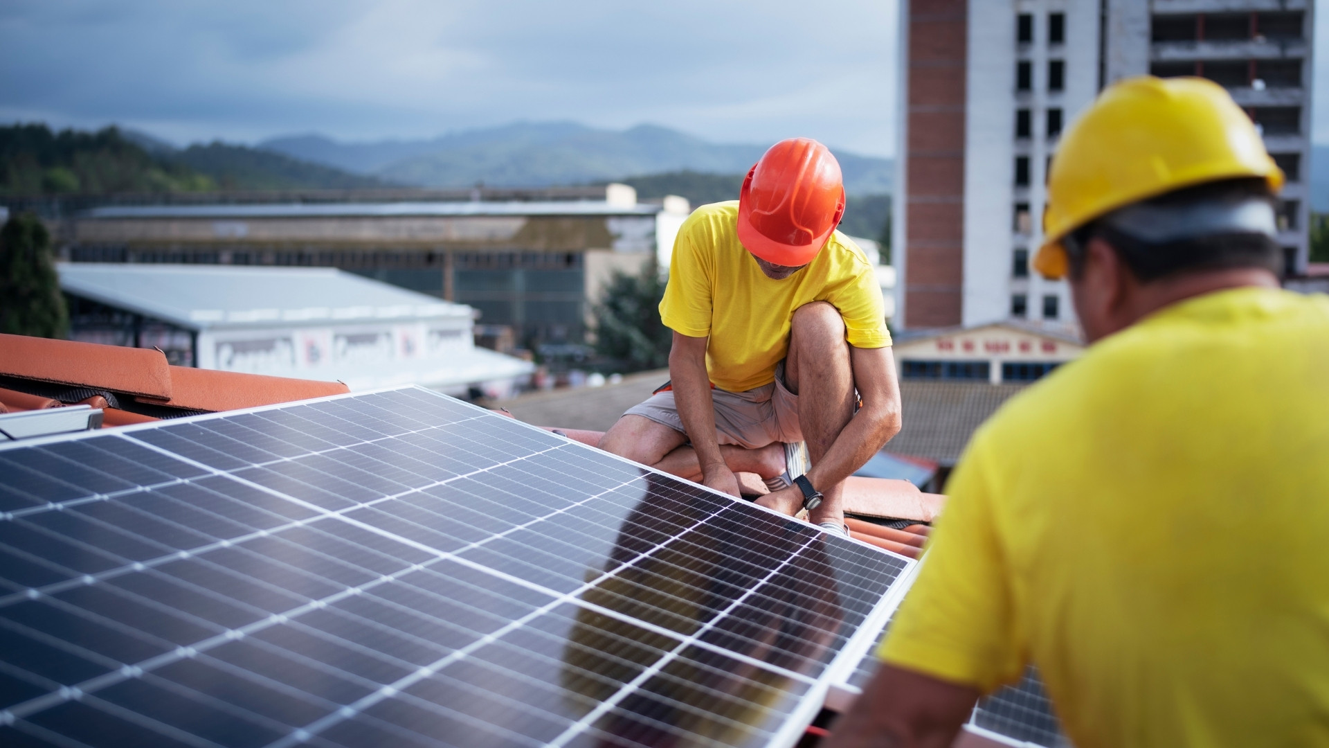 Zwei Handwerker bei der Montage einer Photovoltaikanlage auf einem Bürogebäude von Sunna Energie